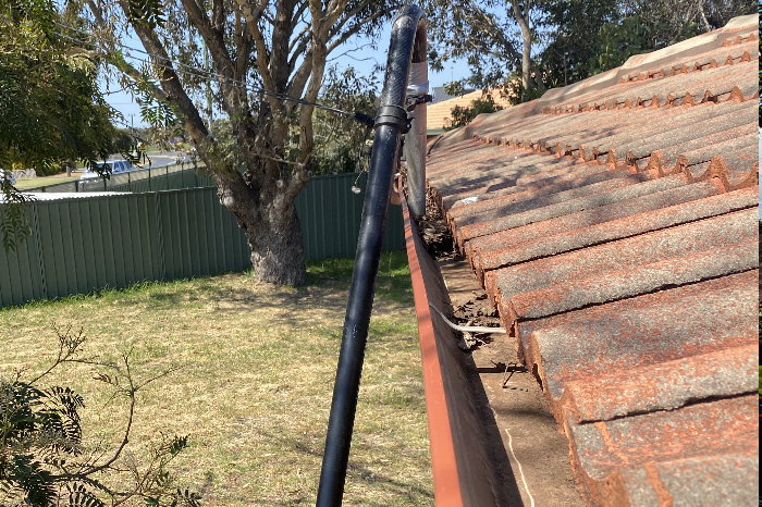 Picture of vacuum gutter cleaning in action, sucking leaves and debris from gutter as it moves along