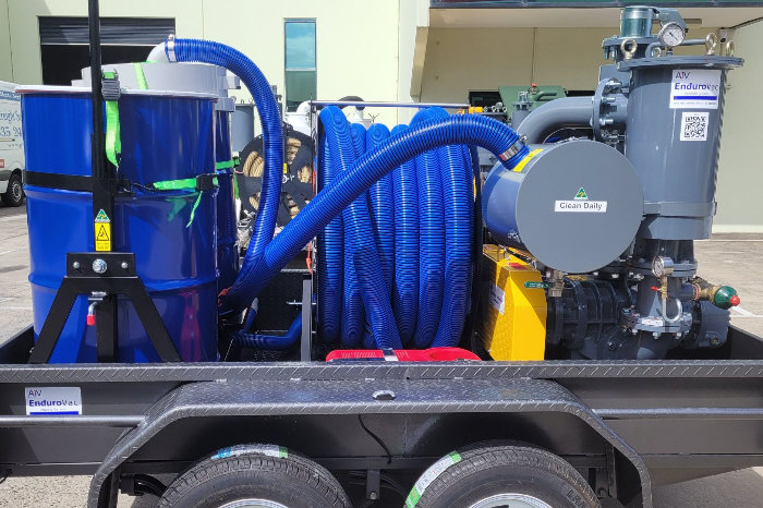 Side view of trailer mounted vacuum cleaning equipment, showing waste drum, motor and coiled hose